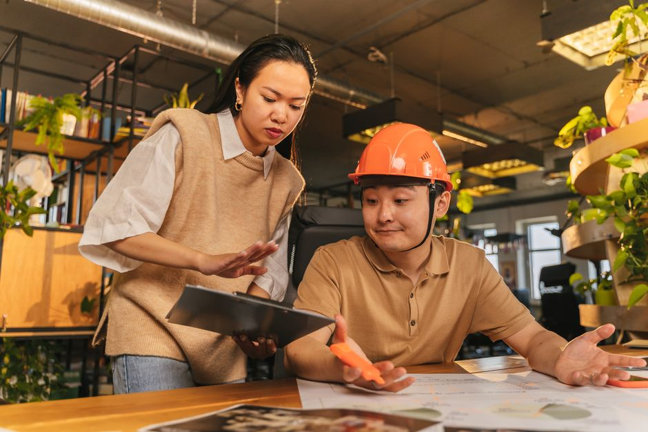 A contractor meeting with another worker at a job site to review plans and responsibilities.
