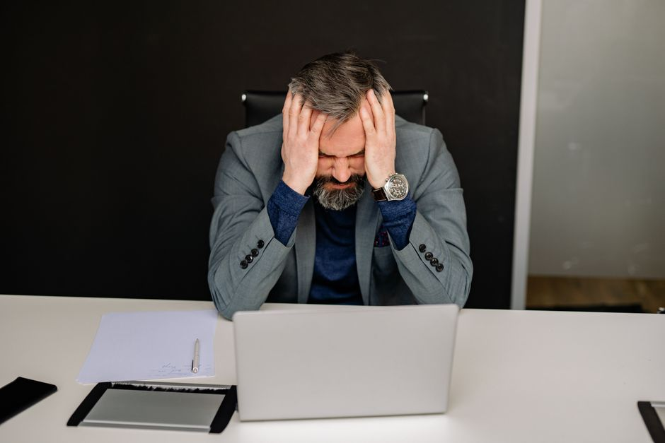 Business owner at a laptop in a small office during a technology disruption or system outage.