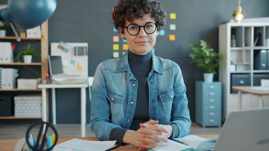 A solo business owner working from a laptop at a simple desk setup with paperwork nearby.