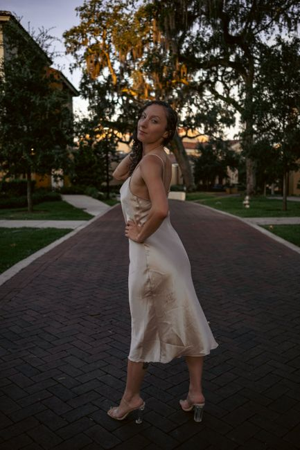 A satin evening dress catching light across the surface, emphasizing shine and formal occasion appeal.
