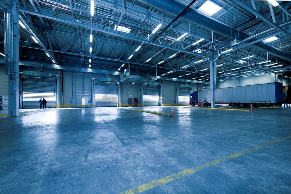 A warehouse loading dock with dock doors, trailers, and pallet traffic areas.