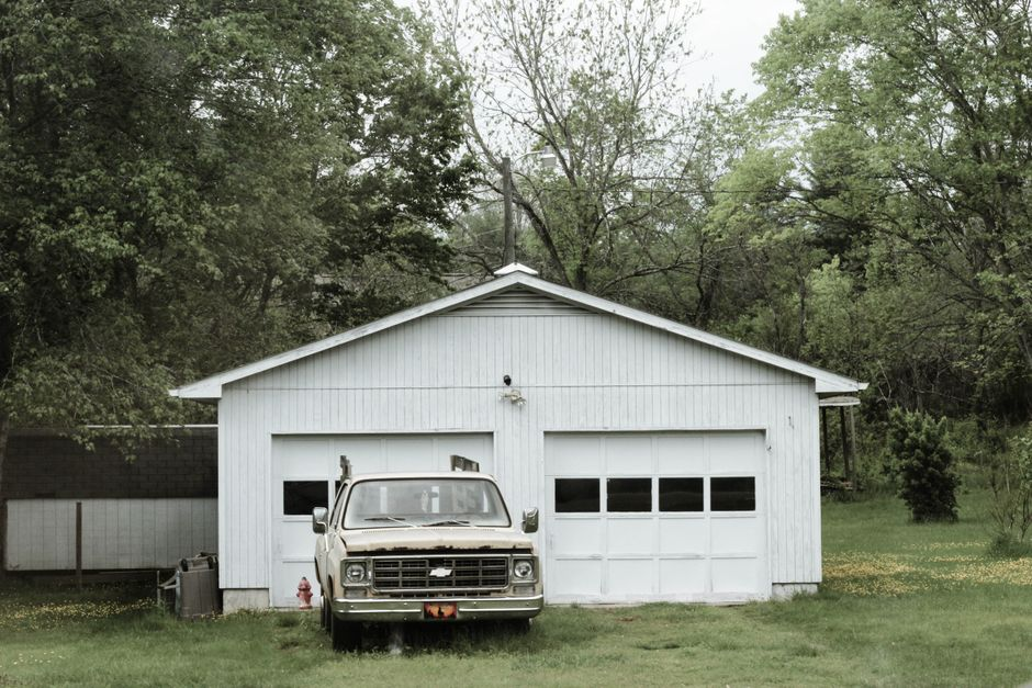A house with an existing garage and a sloped backyard, illustrating different possible locations for added living space.