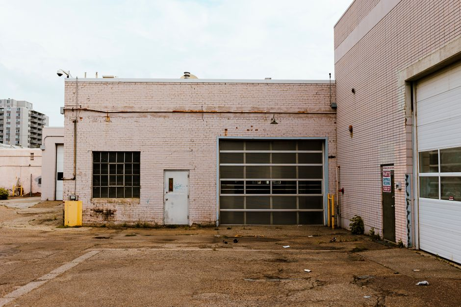 Workers exposing layers of a flat commercial roof during tear-off on an industrial building.