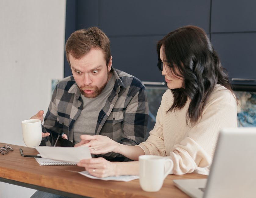 A couple sitting at a table reviewing insurance or financial documents at home.