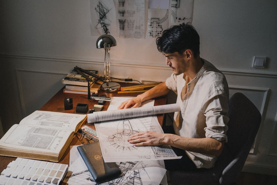 Architectural plans and scaled drawings for a home addition spread across a work table.