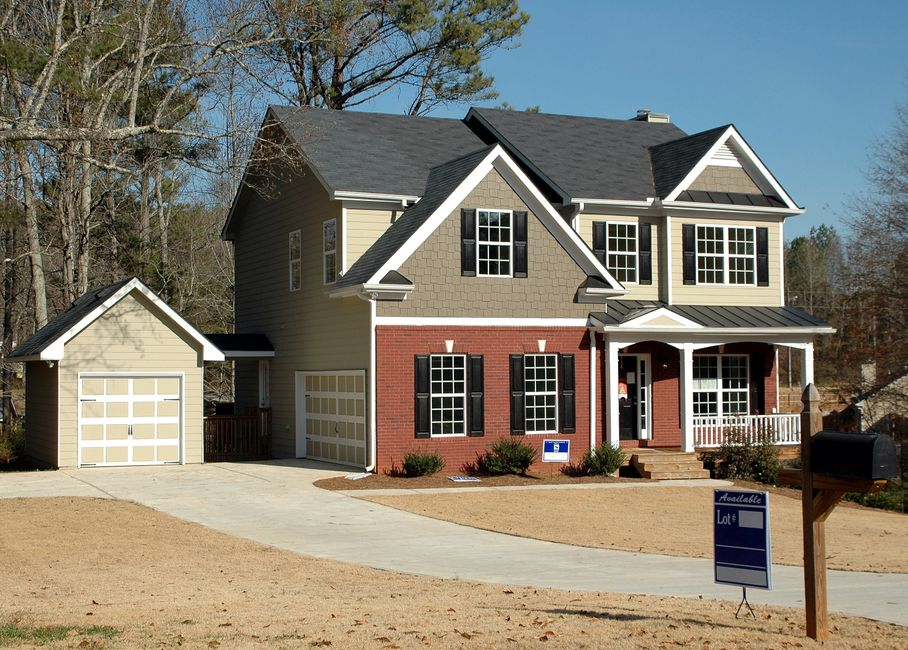 A house exterior during rainy weather showing rooflines, eaves, and a garage-side passage that could allow rodent entry.