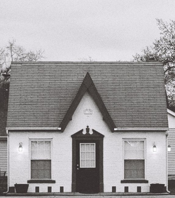 A house exterior during rainy weather with attention on roofline, entry, and wall transitions where water problems can begin.