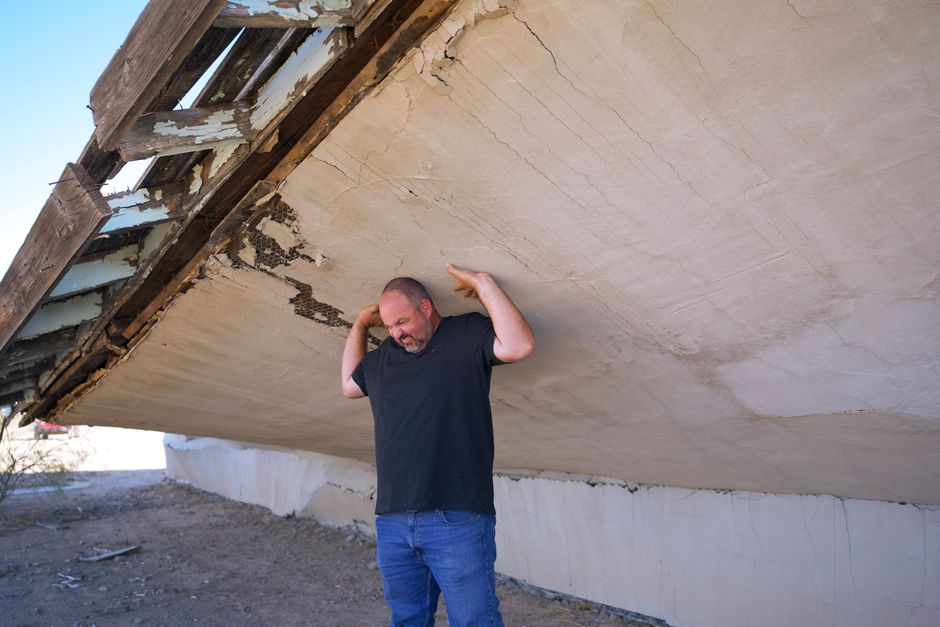 A roofing crew examining exposed roof decking during tear-off, with damaged sheathing visible.