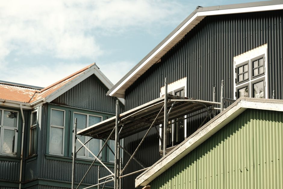 Two neighboring homes featuring different roofing materials, one with metal roofing and one with tile.