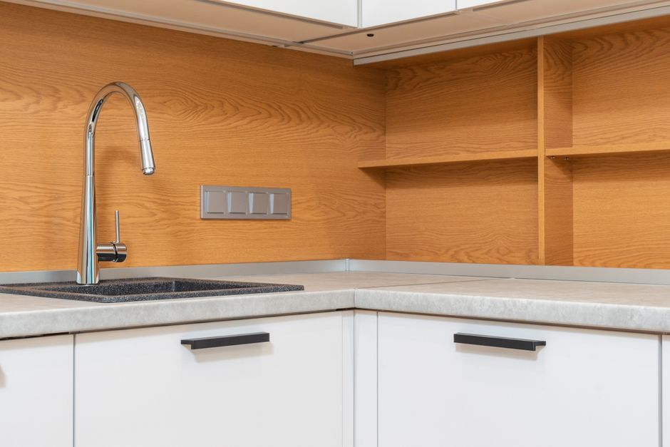 Water staining a kitchen cabinet base and the adjacent wall near the floor.