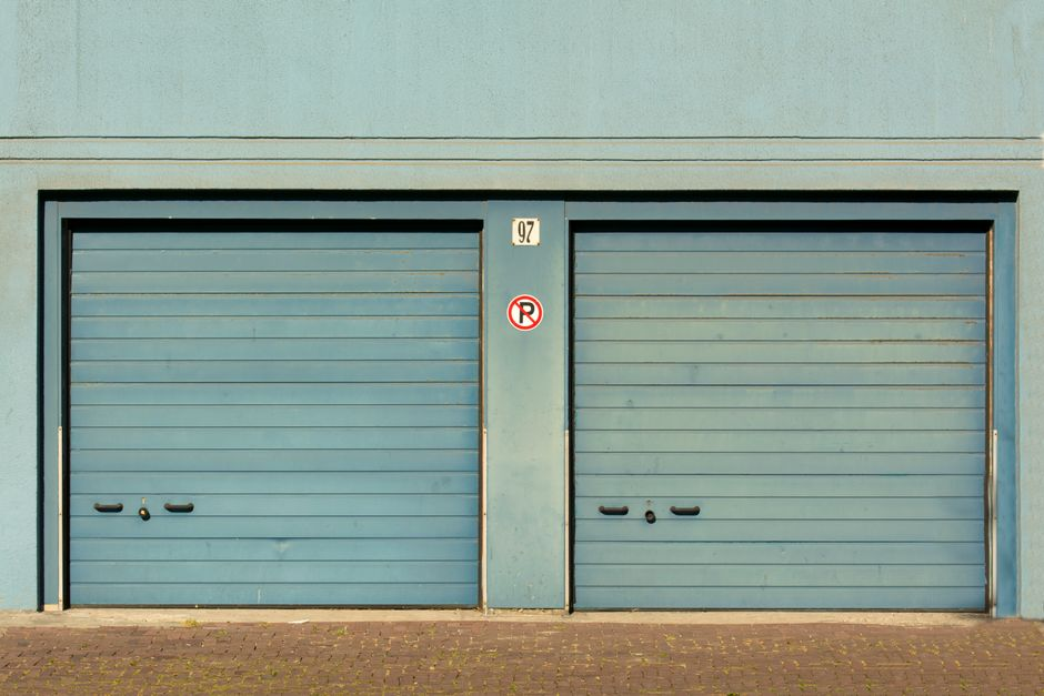 The lower edge of a residential garage door and the ground beside it, where potential entry gaps can be checked.