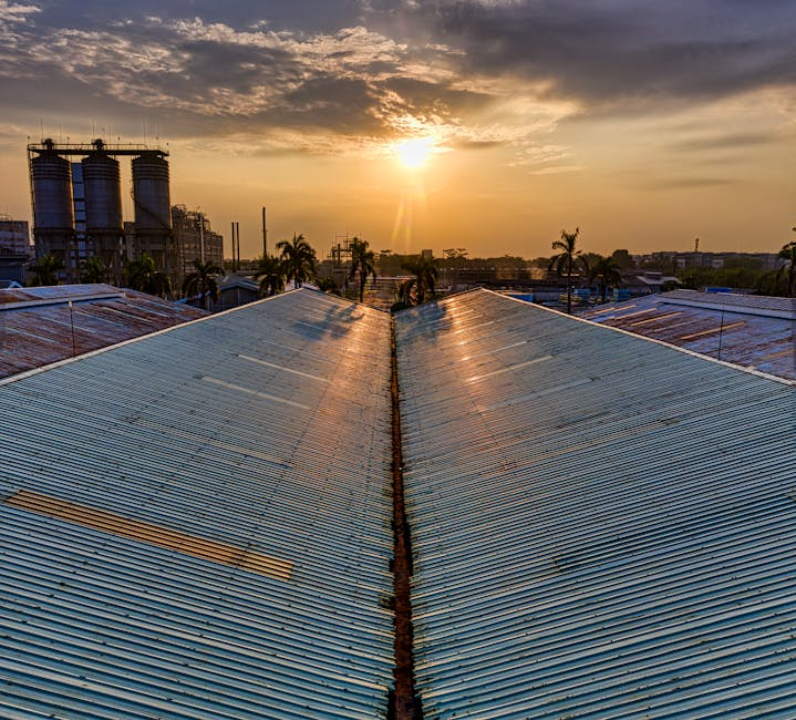 A facility maintenance worker inspecting an industrial roofline and service penetrations.