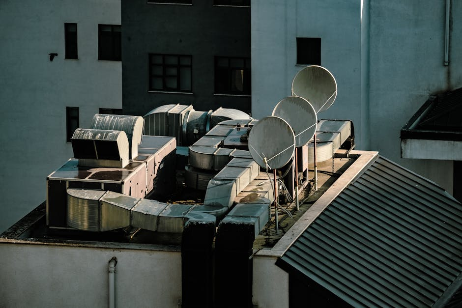 A technician inspecting a commercial rooftop with vents, HVAC units, and roof edges visible.