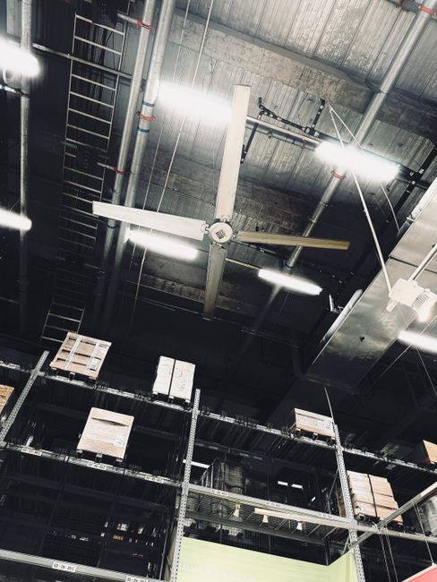 A worker lifting a ceiling tile in a commercial space to inspect overhead utilities and ceiling voids.