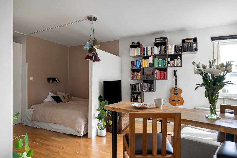 A compact studio-style living space with an open layout, kitchenette, and simple furnishings.