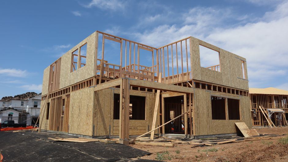 A custom home under construction with exposed framing on a residential lot.