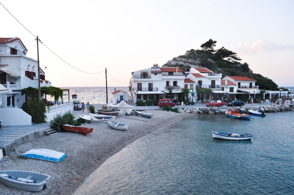 A relaxed seaside village scene with waterfront tavernas, boats, and a calm Aegean backdrop.