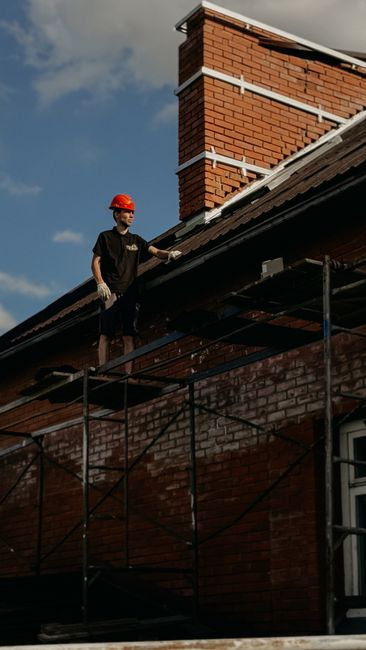 A roofing professional inspecting a large flat commercial roof on an industrial building.