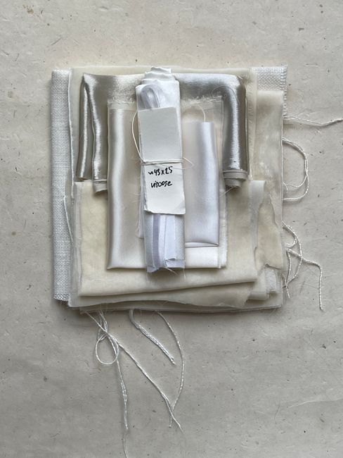 A set of fabric swatches spread across a sewing table for comparing texture, weight, and color.