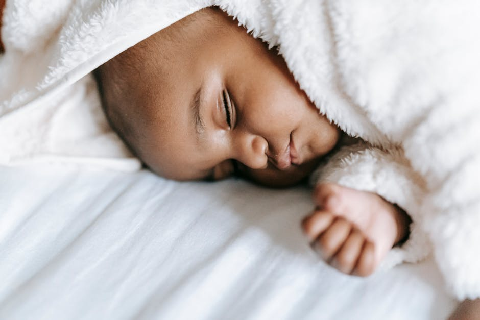 Close view of a baby crib with a firm fitted mattress in a simple nursery.