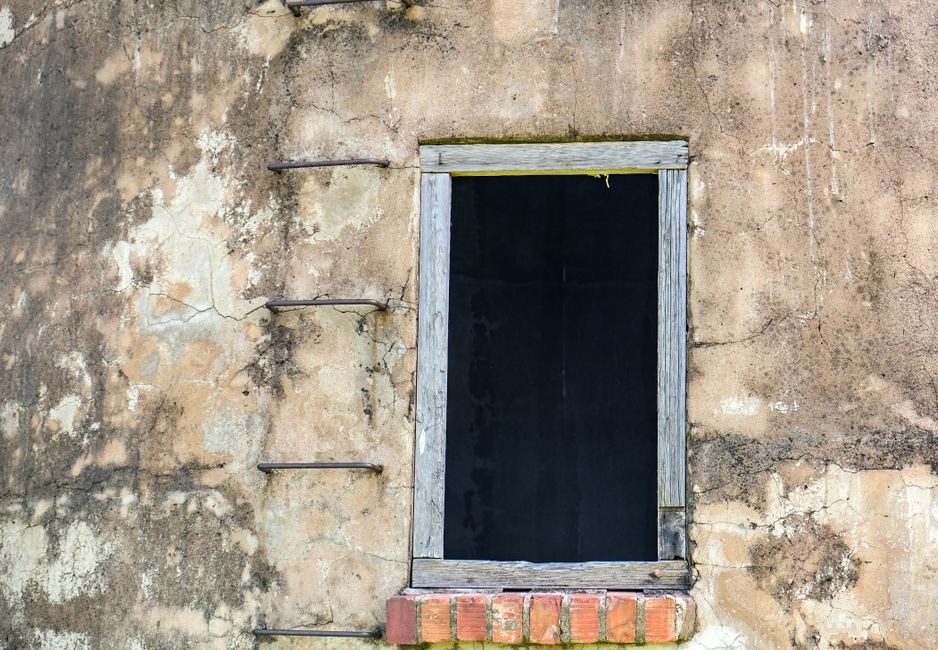 Close-up of an exterior house window with cracked caulk and visible seal wear around the frame.