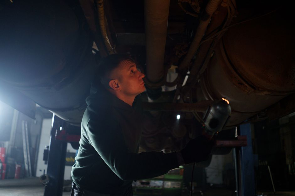 A pest or rodent specialist using a flashlight to inspect an attic or garage for signs of rodent activity.