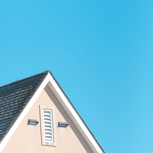 Close-up of a home's roofline and vent area being inspected for small gaps and entry points.
