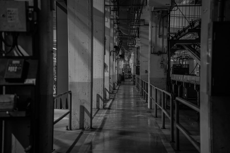 Industrial electrical room with panels and narrow service access in a factory setting.