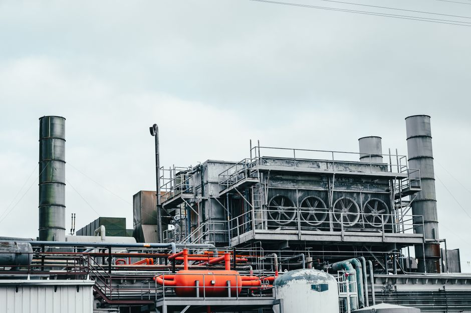 Factory utility infrastructure with exposed conduit, piping, and equipment-adjacent service space.