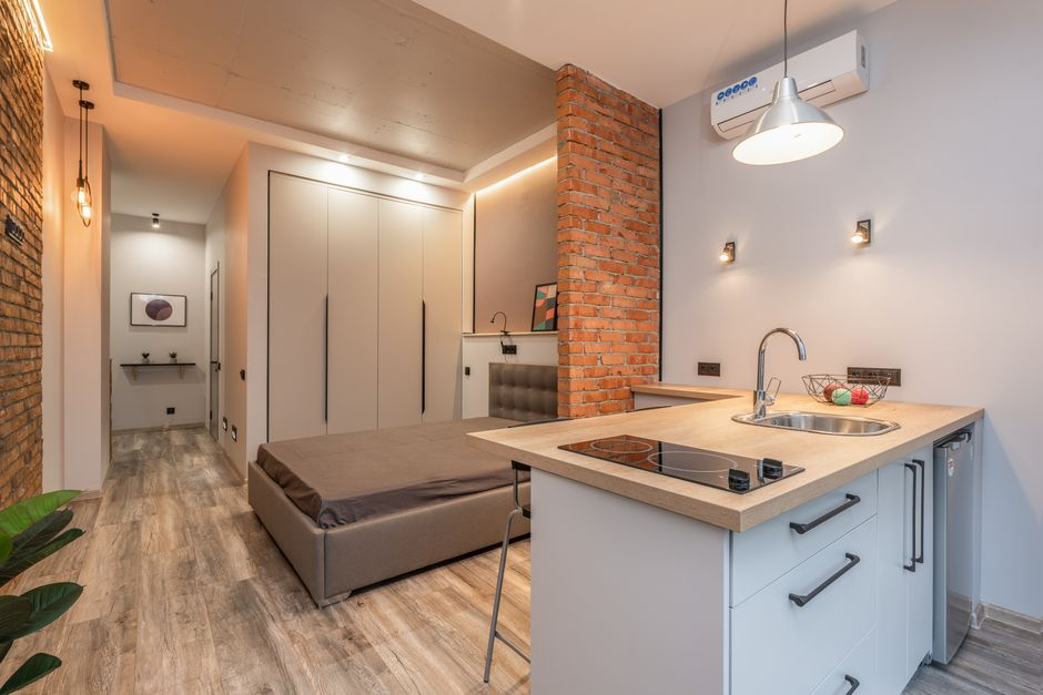 A small guest suite interior with a bed, seating area, and nearby private bathroom.