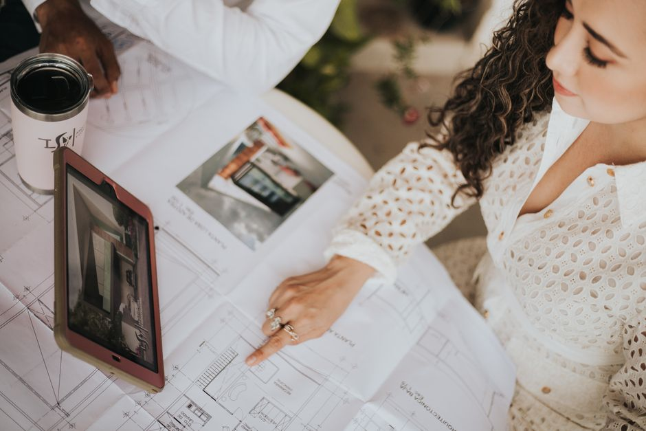 Homeowners and a design professional reviewing detailed house plans across a table.