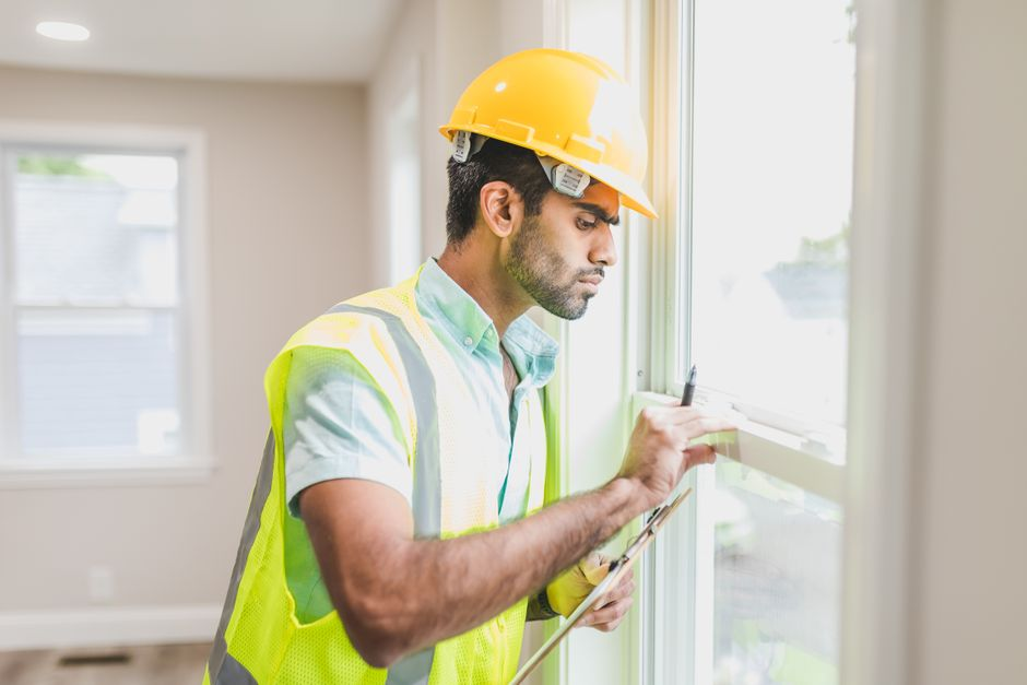 A homeowner and builder reviewing and signing construction documents at a meeting table.