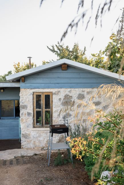 A small detached backyard ADU behind a main house with a path and landscaped yard.
