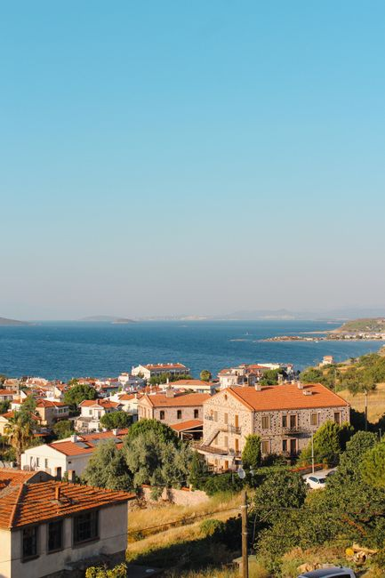 A peaceful Greek coastal village with white buildings overlooking the sea from a hillside.