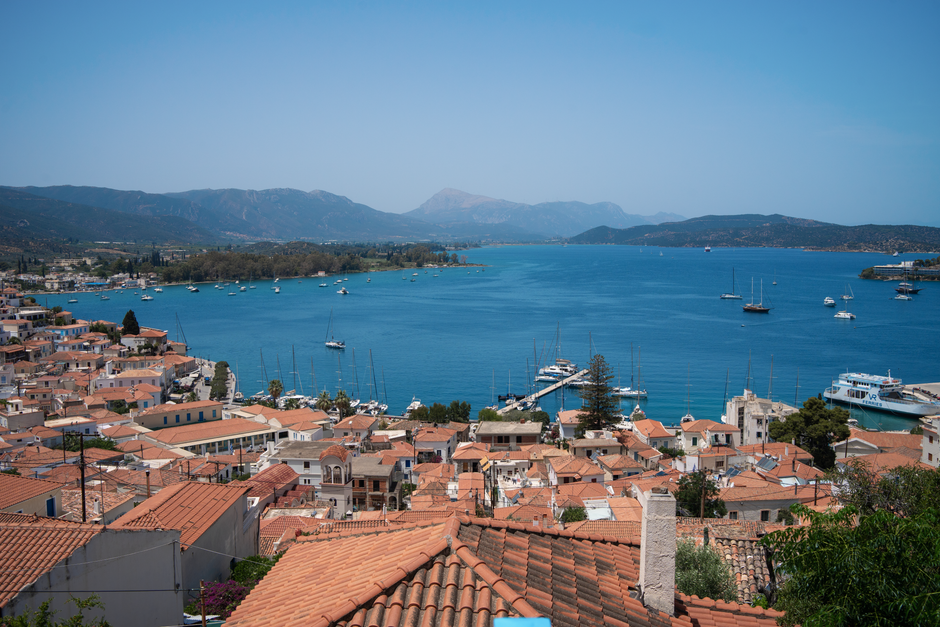A scenic harbor in a Greek seaside village with boats, waterfront buildings, and a relaxed local atmosphere.