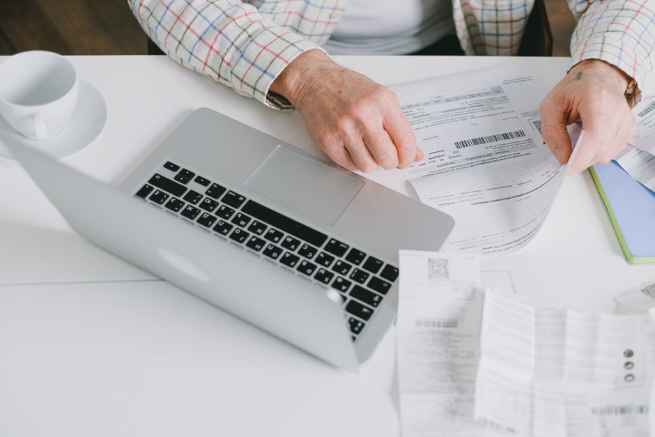 A homeowner comparing multiple roofing estimates and paperwork spread across a kitchen table.