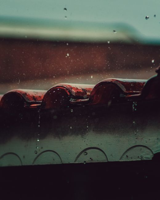 Rain hitting a sloped residential roof during a storm, showing how water can be driven across the surface by wind.