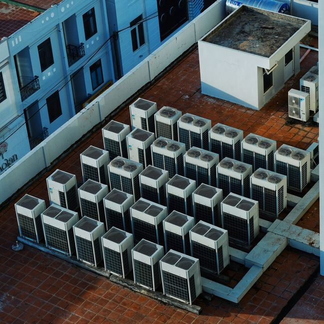Inspector standing on a commercial flat roof with HVAC units and roof details visible.