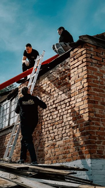 Commercial roofing crew removing old roofing material and staging debris during tear-off.