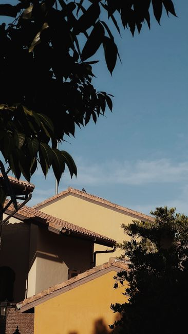 A Southern California-style stucco home with a clay tile roof in bright sun.