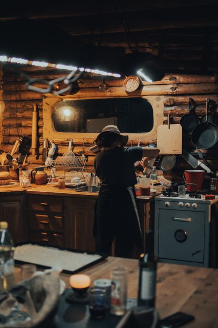A homeowner using a flashlight to inspect a kitchen corner near appliances for signs of rodent activity.
