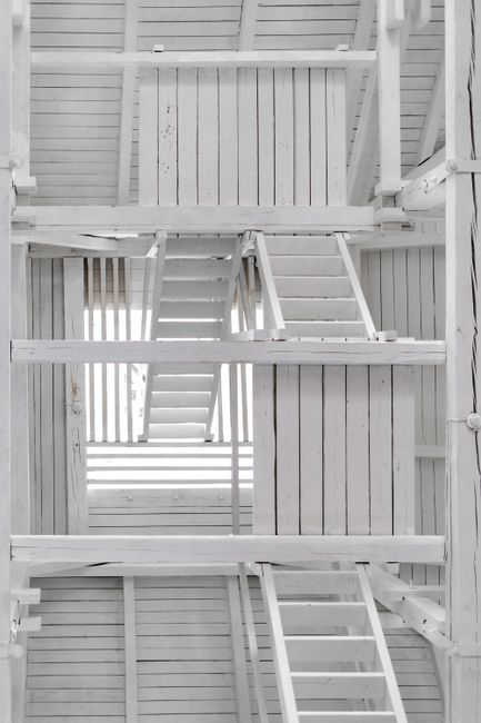 A technician inspecting an attic access point with a ladder and flashlight.