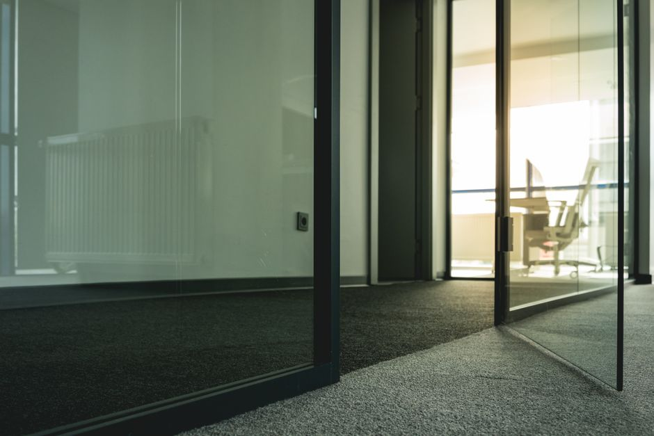 A modern glass office partition shown with one panel clear and another panel frosted for privacy.