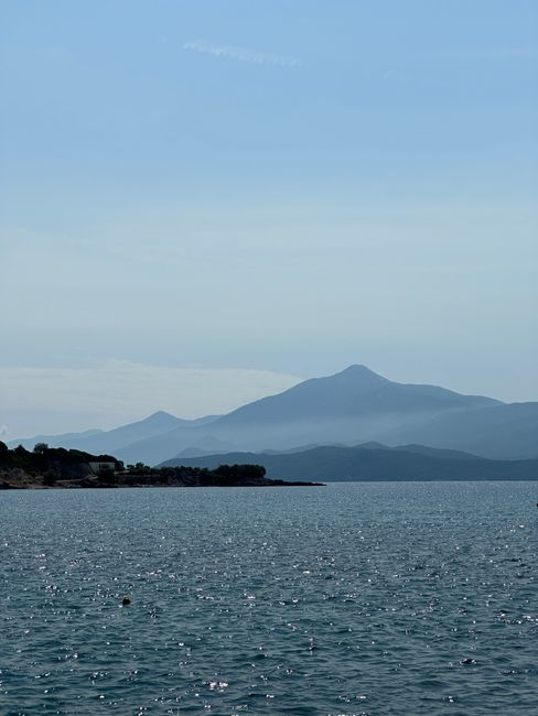 Calm Aegean coastline on a sunny Greek island with clear water and a relaxed late-season atmosphere.