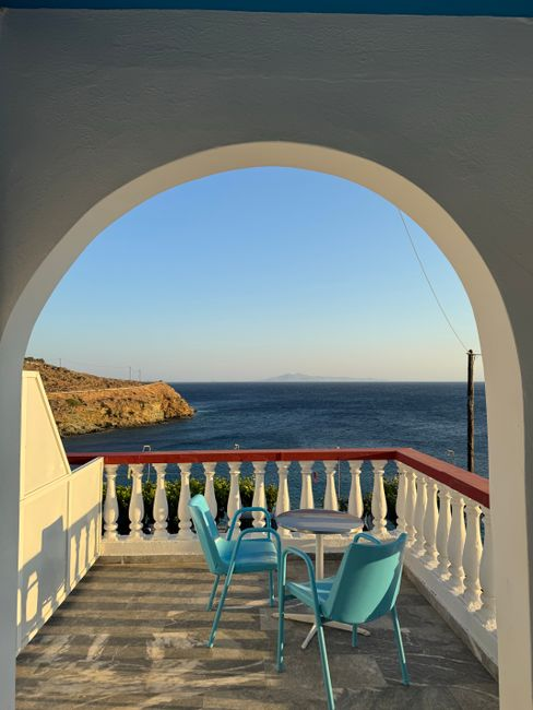 Couple relaxing beside a pool terrace overlooking the sea at a boutique Greek island stay.
