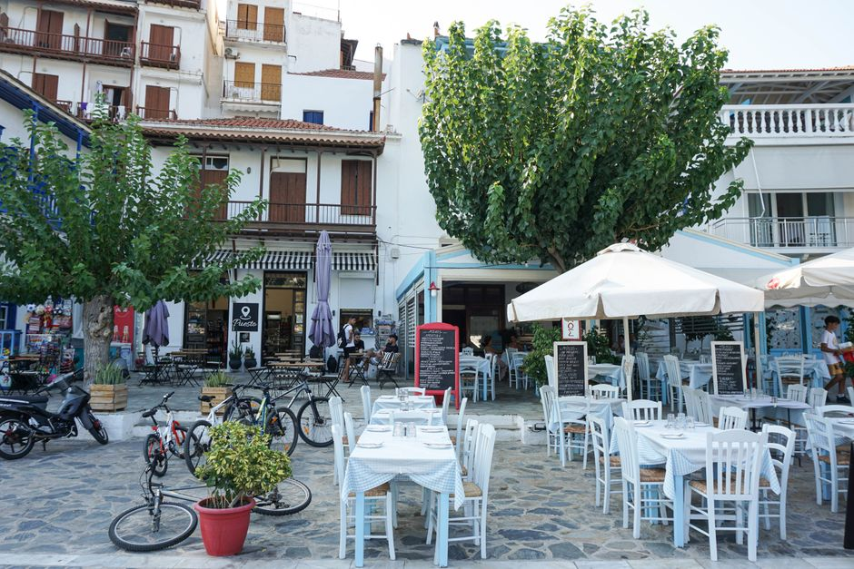An outdoor seaside taverna terrace on a Greek island in the early evening.