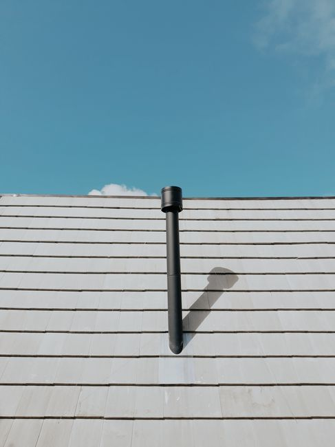 Residential roof showing vulnerable transition points such as a vent, flashing, and roof angles where leaks often begin.