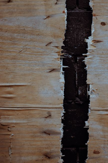 Sunlight highlighting scratches and wear on a hardwood floor in a living space.