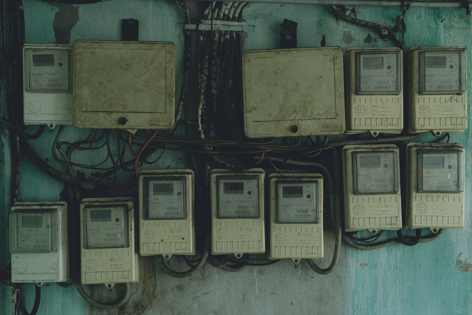 An electrician inspecting an older residential electrical panel with breakers exposed.