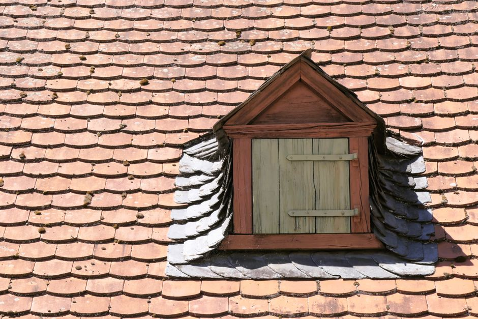 A roofing professional inspecting a residential roof and checking surface and flashing conditions.